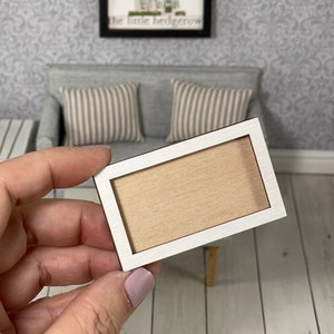 May include: A white wooden frame with a light brown wood insert. The frame is approximately 4 inches wide and 6 inches long.