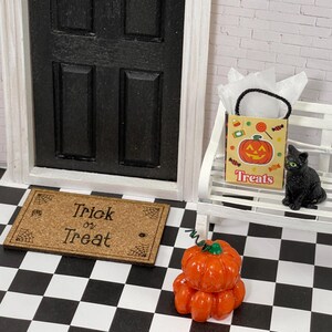 May include: A miniature Halloween scene with a black cat, a pumpkin, a trick or treat doormat, and a bag of treats. The doormat reads "Trick or Treat".