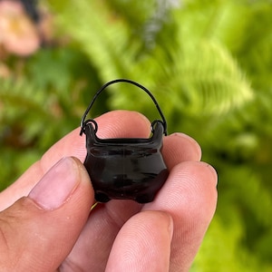 May include: A small black cauldron with a handle, perfect for miniature witch or wizard decor.