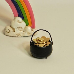 May include: A miniature black pot filled with gold coins, sitting under a rainbow with a white cloud.