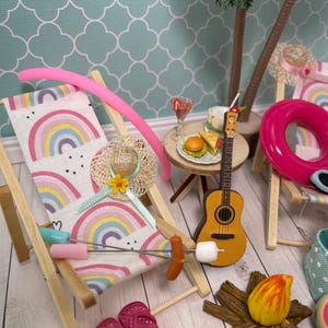 May include: A miniature wooden beach chair with a rainbow-patterned fabric seat, a small acoustic guitar, a round table with a tiny burger and drink, a pink pool noodle, a pair of pink flip-flops, a campfire, and a palm tree accessory.