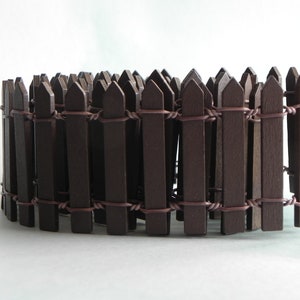 May include: A brown wooden fence made of thin slats connected by wire. The fence is curved into a circle.