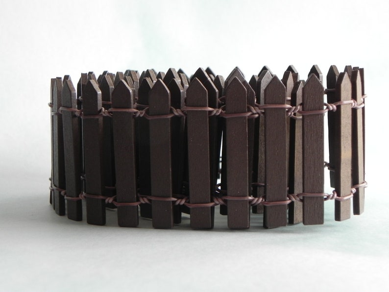 May include: A brown wooden fence made of thin slats connected by wire. The fence is curved into a circle.