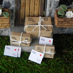 May include: Four miniature cardboard packages tied with twine and decorated with a red stamp. Two white envelopes with a red stamp and a blue wave design are also included.