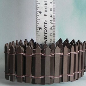 May include: A brown wooden picket fence with wire connecting the pickets. The fence is approximately 2.5 inches tall.  WESTCOTT&reg; FLEXIBLE is printed on a ruler in the background.