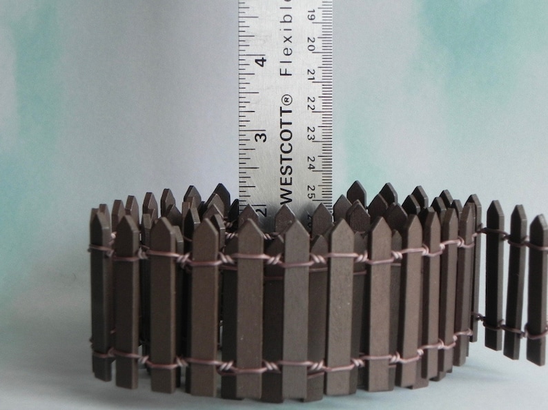 May include: A brown wooden picket fence with wire connecting the pickets. The fence is approximately 2.5 inches tall.  WESTCOTT&reg; FLEXIBLE is printed on a ruler in the background.