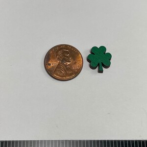 May include: A small green four-leaf clover charm, about the size of a US penny.