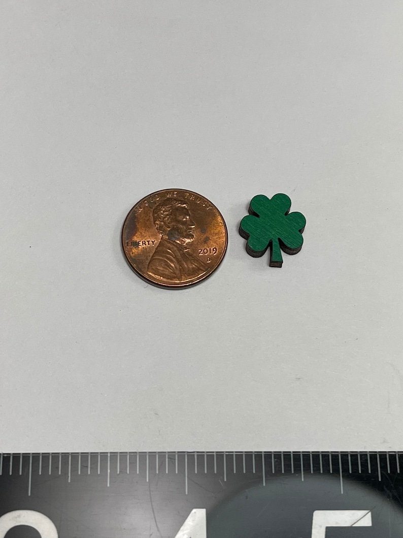 May include: A small green four-leaf clover charm, about the size of a US penny.