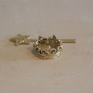 May include: A gold crown with a decorative design and a gold star-shaped wand.