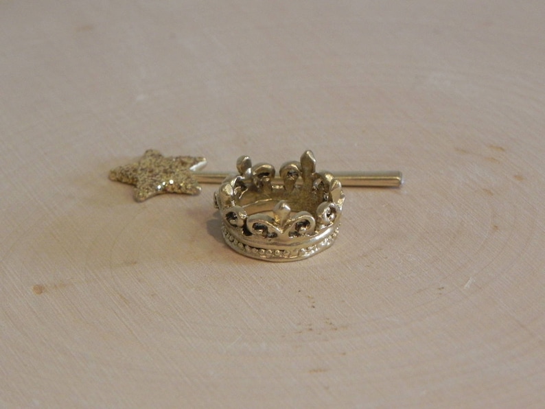 May include: A gold crown with a decorative design and a gold star-shaped wand.