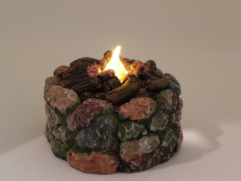 May include: A small, decorative, faux stone fire pit with a glowing light inside, simulating a campfire.