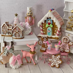 May include: A festive Christmas scene featuring miniature gingerbread houses, a pink deer with a gold collar, a nutcracker, and gingerbread people. The scene includes a gingerbread house, a Christmas tree, and a snowflake cookie.