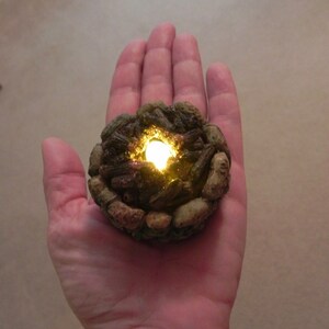 May include: A small, realistic-looking campfire with glowing embers, made of brown and gray materials, and a light inside.