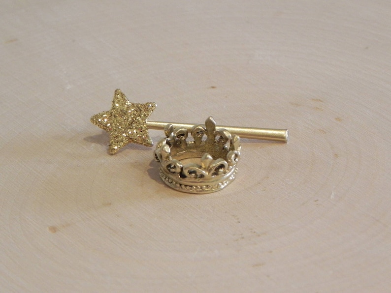 May include: A gold crown with a sparkly star on a stick. The crown is detailed with intricate designs and the star is made of glitter.