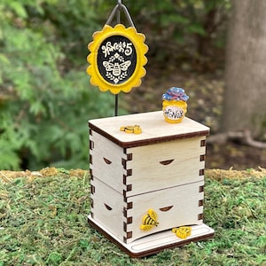 May include: A wooden beehive with two drawers, a small honey jar, and a yellow sign that says "Honey $5" with a bee illustration.