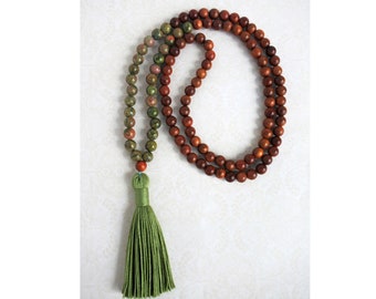 May include: A green and brown beaded mala necklace with a green tassel. The necklace is made of wood and gemstone beads.