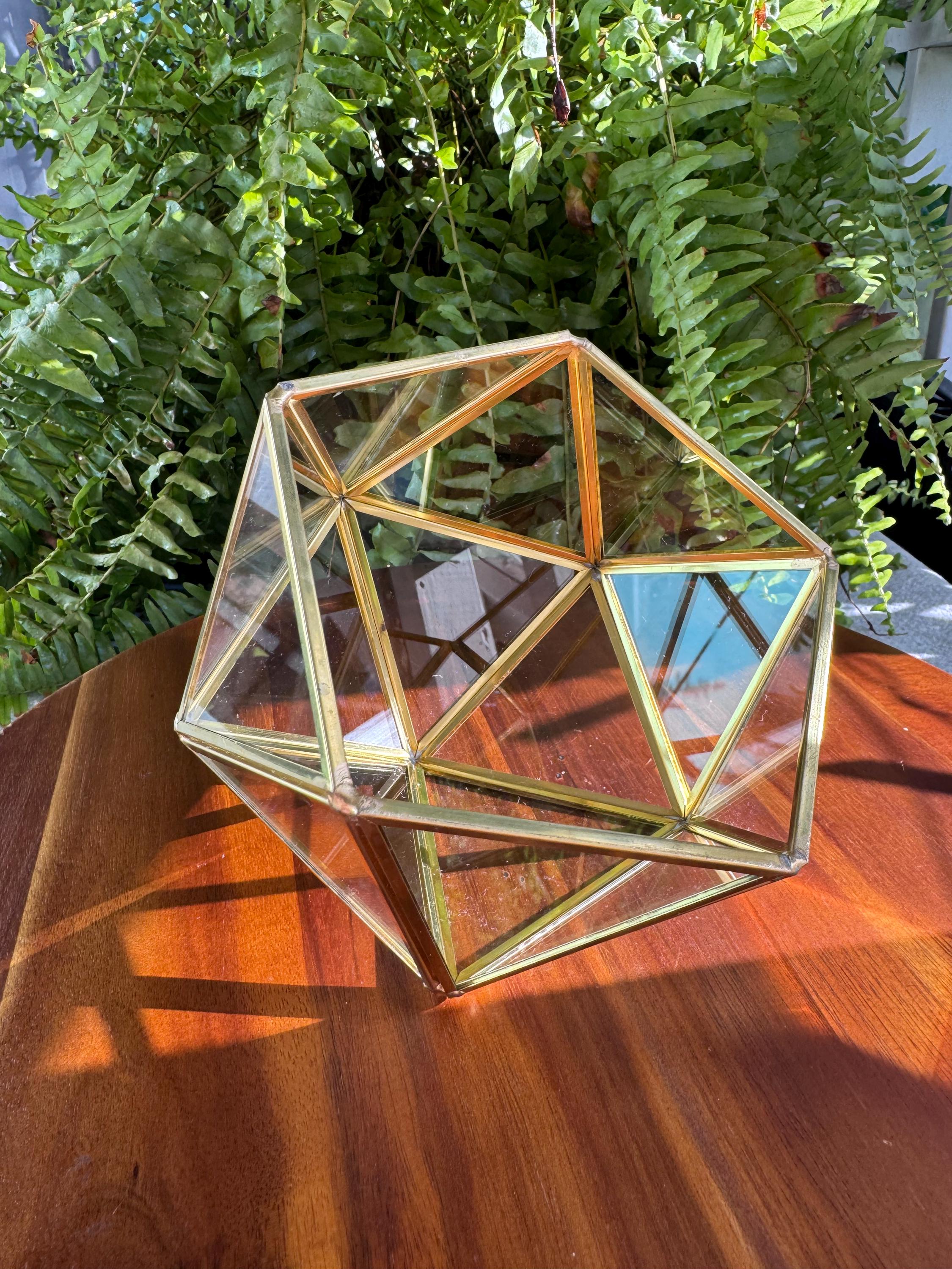 Geometric glass terrarium glass and brass sits on a tip