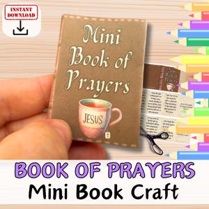 May include: A miniature brown "Mini Book of Prayers" is held in a hand. The cover features a pink teacup with "JESUS" on it. The book is a craft item with the words "BOOK OF PRAYERS Mini Book Craft".