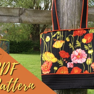 Pode incluir: Duas bolsas de mão acolchoadas penduradas em uma cerca de madeira. A bolsa à direita tem um fundo preto com um padrão floral de papoulas rosa, amarelas e vermelhas. A bolsa à esquerda tem um tecido estampado colorido. O texto "PDF Pattern" está em primeiro plano.