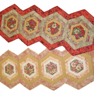 May include: Two table runners made of fabric with a hexagonal pattern. The top runner is red and green with floral designs. The bottom runner is yellow and pink with floral designs.