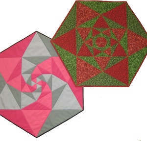 Puede incluir: Dos manteles hexagonales con patrones geométricos. Un mantel es rosa, gris y blanco con un diseño en espiral. El otro mantel es rojo, verde y blanco con un diseño de estrella.