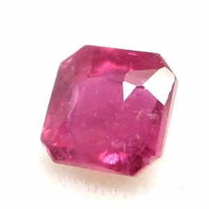 May include: A pink gemstone with a square emerald cut.