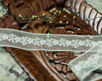 Puede incluir: Borde de encaje blanco con un patrón floral sobre un fondo de madera.