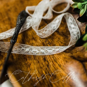 May include: A black wand with a white lace ribbon on a wooden surface. The text "Catheryn Collins" is visible in the bottom right corner of the image.