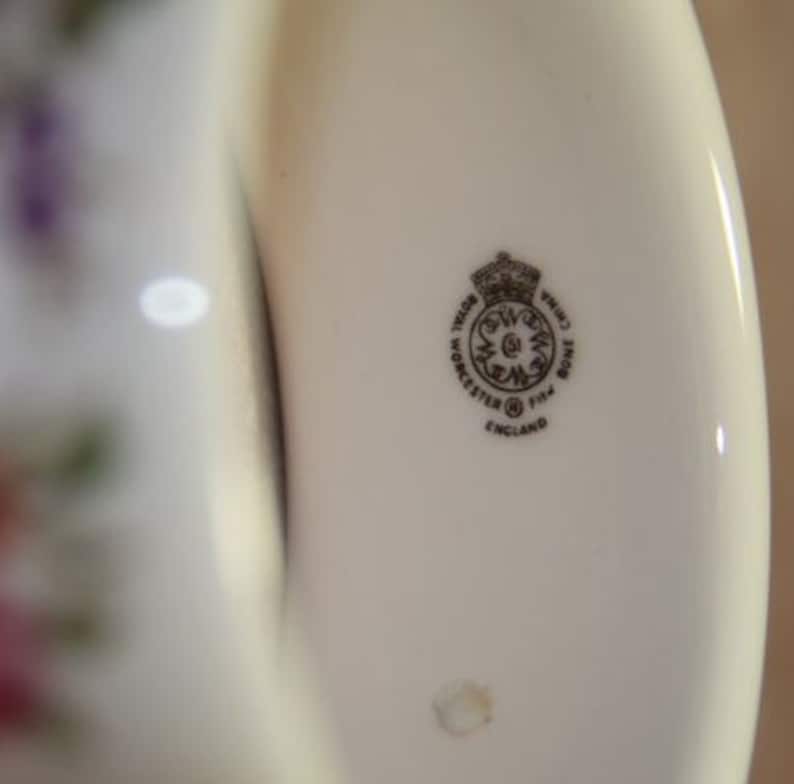 Peut inclure: Gros plan d'une assiette en porcelaine blanche avec un logo noir et blanc qui indique "Royal Worcester Fine Bone China Made in England".