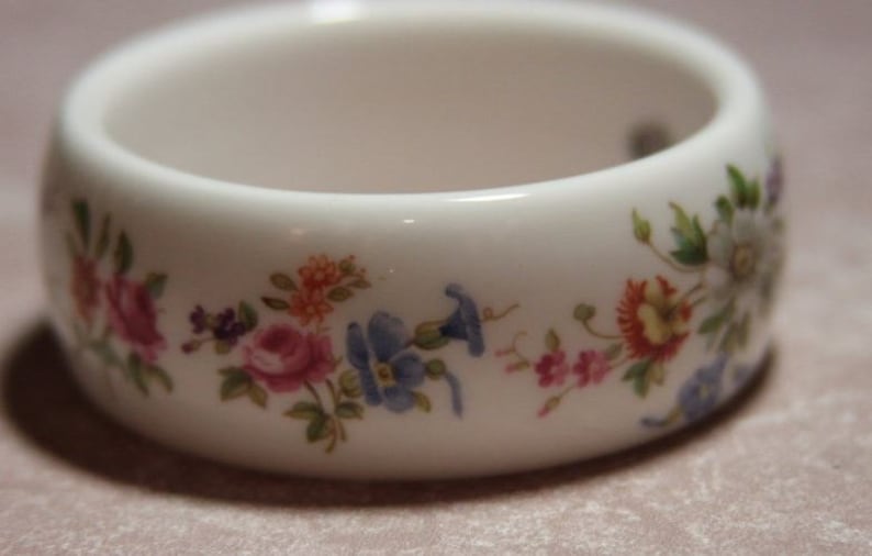 Peut inclure: Bracelet en c&eacute;ramique blanche avec un motif floral. Les fleurs sont roses, bleues, jaunes et vertes.
