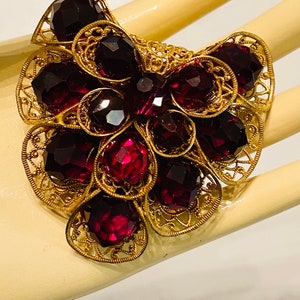 May include: A gold filigree brooch with a cluster of deep purple faceted glass stones.