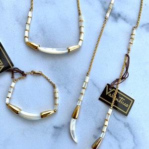 Puede incluir: Un conjunto de tres collares de oro con detalles de concha blanca. Los collares presentan una forma de media luna y est&aacute;n hechos con peque&ntilde;as cuentas redondas. Los collares est&aacute;n etiquetados como "Valentino".