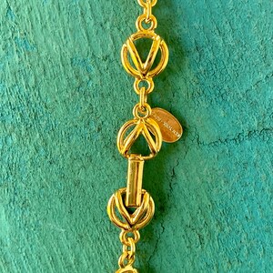 May include: Gold-toned necklace with a chain made of interlocking circles and V-shaped links. The necklace has a clasp with a small tag that reads "NEW YORK, NEW YORK".