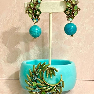 May include: A set of vintage earrings and a brooch featuring a leafy design with green and blue rhinestones and turquoise-colored beads.