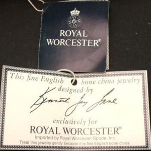 Peut inclure: Une &eacute;tiquette blanche avec du texte noir qui dit "This fine English bone china jewelry designed by  exclusively for ROYAL WORCESTER Imported by Royal Worcester Spode, Inc. Treat this jewelry gently because it is fine English bone china."