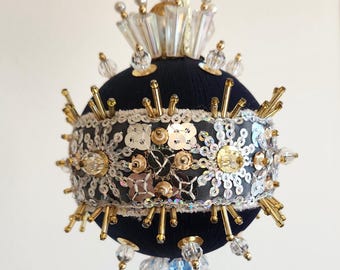 May include: A black velvet Christmas bauble decorated with gold and silver sequins, beads, and a crystal-like drop.