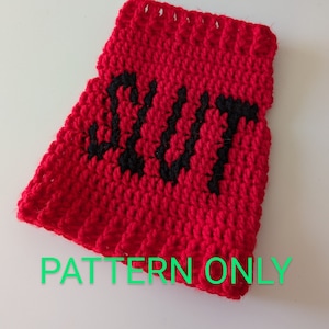 Könnte beinhalten: Ein rotes gehäkeltes Objekt mit dem Wort "SLUT" in schwarzen Buchstaben. Der Text "PATTERN ONLY" ist in grünen Buchstaben am unteren Rand des Objekts geschrieben. Bei dem Objekt handelt es sich wahrscheinlich um eine Häkelanleitung.