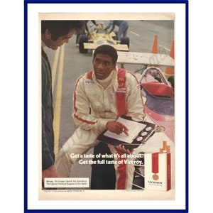 Può includere: Pubblicità vintage con un pilota di auto da corsa in tuta bianca e rossa, seduto e che esamina un blocco per appunti. L'annuncio include il testo: "Get a taste of what it's all about. Get the full taste of Viceroy."