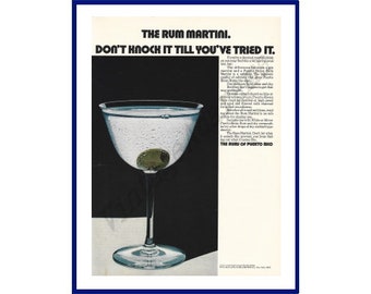 May include: A vintage print advertisement for Puerto Rican rum. The ad features a martini glass filled with a clear liquid and a green olive. The text reads "The Rum Martini. Don't knock it till you've tried it. The Rum of Puerto Rico."