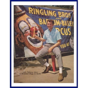 Könnte beinhalten: Vintage Zirkusplakat mit dem Text "Ringling Bros and Barnum & Bailey Circus" und einem Clown-Gesicht. Ein Mann in einem hellblauen Hemd und grauer Hose sitzt vor dem Plakat auf einem Hocker. Der Text "Jack Palance stars in 'Greatest Show on Earth'" ist ebenfalls sichtbar.