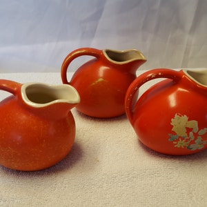 Ceramic pitchers, three small red, one with a decal