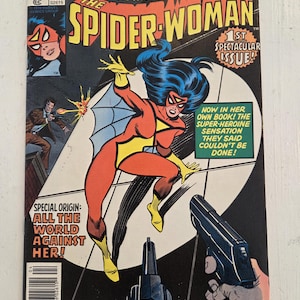 May include: Spider-Woman comic book cover. The cover features Spider-Woman in a dynamic pose, with a red and yellow costume, blue hair, and a web. The comic is titled "The Spider-Woman" and includes text "To Know Her Is To Fear Her!" and "1st Spectacular Issue!"