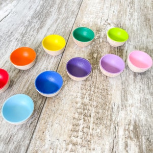 May include: A set of ten small wooden bowls in a rainbow of colors, arranged in a semi-circle on a light wood surface.