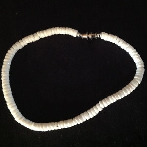 May include: A white shell necklace with a silver clasp.