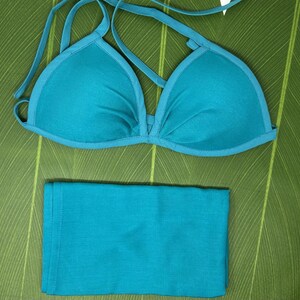 May include: A teal blue bikini top and bottom. The top is a triangle style with adjustable straps. The bottom is a simple, solid piece.