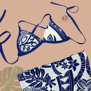 May include: A white and blue bikini set with a matching sarong. The bikini top is a triangle style with blue straps and trim. The sarong and bikini feature a Polynesian-inspired design with floral and geometric patterns.
