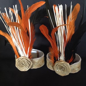 May include: Two woven headbands with orange and black feathers and a woven flower accent.