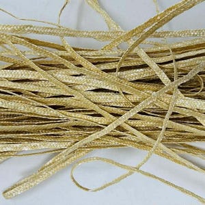 May include: A pile of woven, flat, gold-colored ribbon. The ribbon is made of a shiny material and is arranged in a tangled heap. The ribbon appears to be new and unused, suitable for crafts or gift wrapping.