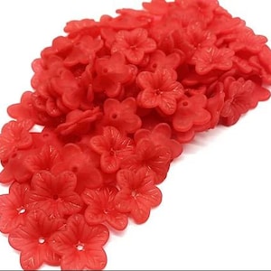 May include: A large pile of red plastic flower-shaped beads. The beads are all the same size and shape, and they are arranged in a random pattern.