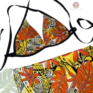 May include: A two-piece bikini set featuring a vibrant floral pattern. The top is a triangle style with black straps and trim. The fabric showcases orange flowers and leaves on a yellow and white background. The bottom piece is also visible.